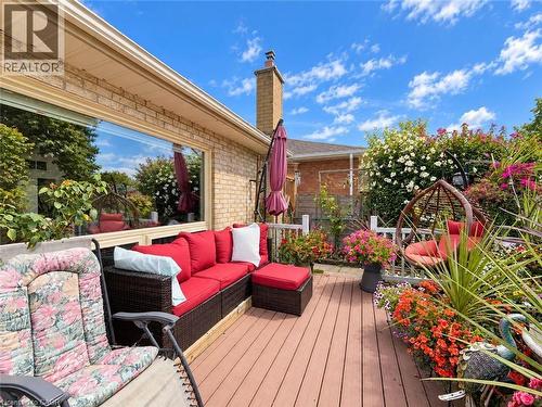 Expansive outdoor deck with a wood-finish surface, surrounded by mature flowering plants and a brick exterior - 1236 Thorpe Road, Burlington, ON 