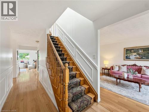 Hardwood flooring, wood staircase with carpeted treads, decorative wall paneling, and a bright interior - 1236 Thorpe Road, Burlington, ON 