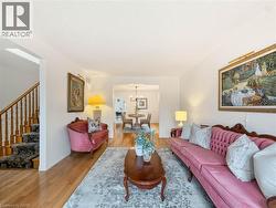 Hardwood flooring, painted white walls, and a staircase with wood banister and carpeted treads - 