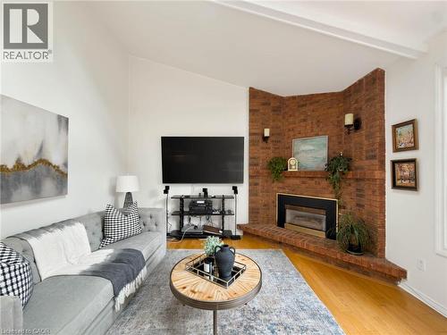 Vaulted ceilings, brick fireplace, wood-finish flooring, and wall sconces - 1236 Thorpe Road, Burlington, ON 