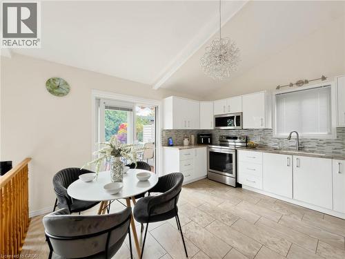 Kitchen featuring white cabinetry, stainless steel appliances, a tile backsplash, and light wood-finish flooring - 1236 Thorpe Road, Burlington, ON 