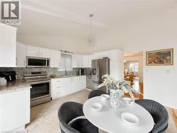 Kitchen featuring white cabinetry, stainless steel appliances, a multi-tone tile backsplash, and light-toned flooring - 
