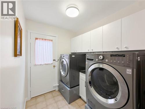 Laundry area featuring tile flooring, white upper cabinetry with knob hardware, and a ceiling-mounted light fixture - 1236 Thorpe Road, Burlington, ON 
