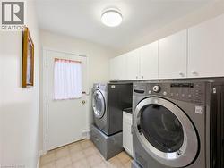 Laundry area featuring tile flooring, white upper cabinetry with knob hardware, and a ceiling-mounted light fixture - 
