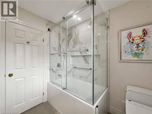 Tub and shower combination with glass enclosure, marble-patterned tile, and recessed shelving - 1236 Thorpe Road, Burlington, ON 