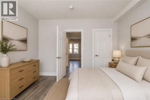 Light gray wall finish, wood-finish flooring, white trim, white paneled doors, and an open doorway - 23 Gibson Avenue, Hamilton, ON 