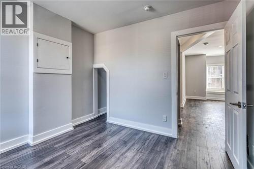 Wood-finish flooring throughout, bright walls, white trim, and a paneled interior door - 23 Gibson Avenue, Hamilton, ON 