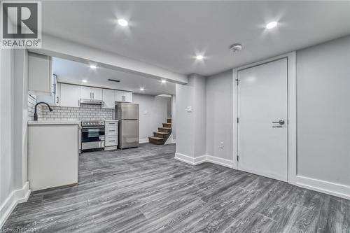 Kitchen area featuring white cabinetry, subway tile backsplash, stainless steel appliances, and a matte black faucet - 23 Gibson Avenue, Hamilton, ON 