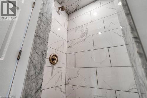 Shower featuring white and grey veined tile, a bronze-finish showerhead, and a matching bronze-finish control knob - 23 Gibson Avenue, Hamilton, ON 