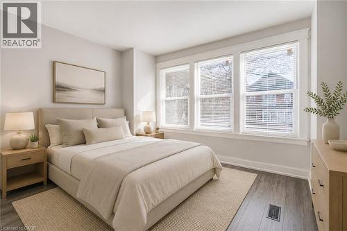 Three large windows with blinds, wood-finish flooring, and light-toned walls - 23 Gibson Avenue, Hamilton, ON 
