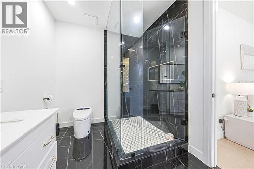 Glass-enclosed shower with black marble-look tile, white patterned shower pan, and dark hardware - 4511 Guelph Line, Burlington, ON 