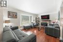 Spacious living area featuring wood-finish flooring, a stone-clad fireplace with a dark metal insert, and a large bay window - 1063 Joan Drive, Burlington, ON 