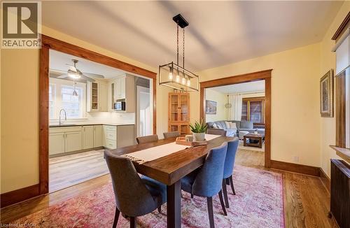 Dining area with wood-finish flooring, a linear chandelier, and wood trim around the doorways - 90 Brock Street, Kitchener, ON 