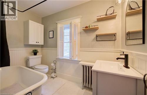 Bathroom featuring a freestanding tub, white beadboard wainscoting, wall-mounted storage cabinet, and a single vanity with a black faucet - 90 Brock Street, Kitchener, ON 