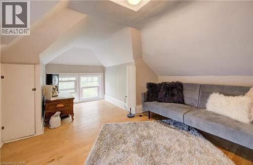 Vaulted ceiling with a flush-mount light fixture, built-in storage cabinet, wood-finish flooring, and multiple windows - 90 Brock Street, Kitchener, ON 