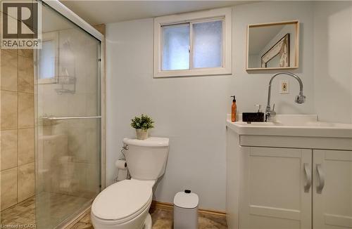 Glass-enclosed shower with tiled walls and floor, white vanity with integrated sink, chrome gooseneck faucet, and white framed mirror - 90 Brock Street, Kitchener, ON 