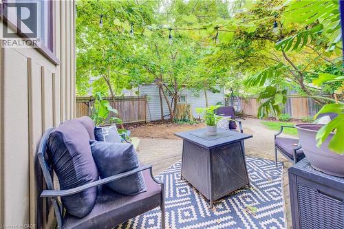 Private outdoor patio with a patterned area rug, surrounded by mature trees, and a wood privacy fence - 90 Brock Street, Kitchener, ON 