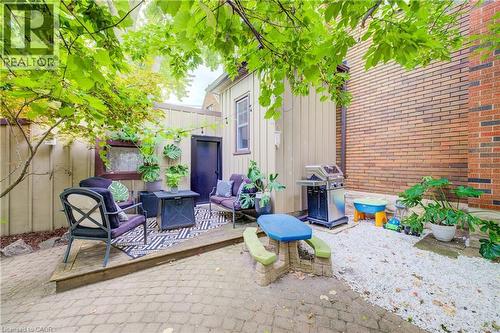 Outdoor space with brick and wood-paneled walls, a paved patio, and a raised wooden deck - 90 Brock Street, Kitchener, ON 