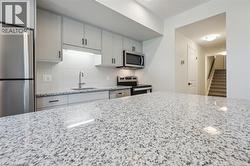 Granite countertops, stainless steel appliances, light gray cabinetry, subway tile backsplash, and built-in microwave - 