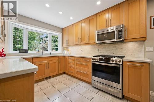Light-toned wood cabinetry with stainless steel hardware, a stainless steel range and microwave, light-toned countertops, and a bay window - 334 Coleridge Drive, Waterloo, ON 