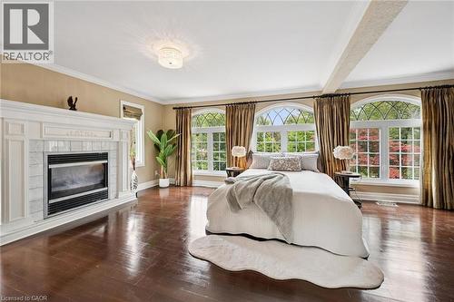Hardwood flooring, ornate fireplace with white mantel, two arched windows with decorative grilles, transom window, and a ceiling-mounted light fixture - 334 Coleridge Drive, Waterloo, ON 