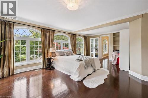 Luxurious primary bedroom suite featuring expansive wood-finish flooring, custom built-in cabinetry, abundant natural light from multi-pane French doors and transom windows, and elegant drapery with d - 334 Coleridge Drive, Waterloo, ON 