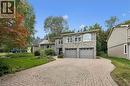 Stone facade residence featuring a paver driveway with a circular inlay, two garage doors, arched windows, and mature landscaping - 334 Coleridge Drive, Waterloo, ON 