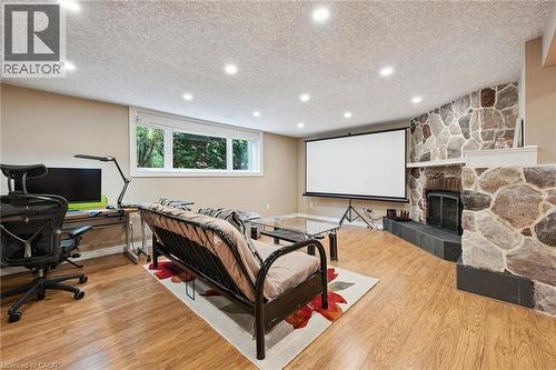 Stone-clad fireplace with a hearth, wood-finish flooring, recessed lighting, and a window - 334 Coleridge Drive, Waterloo, ON 