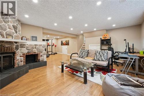 Stone and brick fireplace with a raised hearth, wood-finish flooring, recessed ceiling lighting, and neutral wall tones - 334 Coleridge Drive, Waterloo, ON 