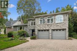 Stone facade with arched windows, an intricate paver driveway, and an attached two-car garage - 