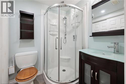 Enclosed glass shower stall, dark wood-finish vanity with frosted glass countertop, wall-mounted mirror, and chrome faucet - 334 Coleridge Drive, Waterloo, ON 
