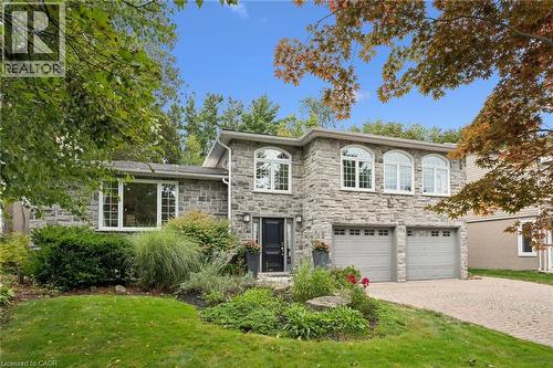 Stone exterior featuring multiple arched windows, a two-car garage, and a paver driveway - 334 Coleridge Drive, Waterloo, ON 