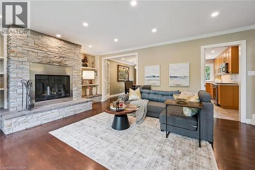 Stone-clad fireplace with a hearth, recessed lighting, wood-finish flooring, built-in shelving, and crown molding - 334 Coleridge Drive, Waterloo, ON 
