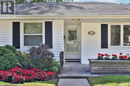 White siding exterior with dark shutters, concrete walkway, and a stone-faced planter box - 948 Long Drive, Burlington, ON 