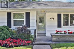 White siding exterior with dark shutters, concrete walkway, and a stone-faced planter box - 