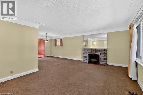 Stone-faced fireplace with a hearth, wall-mounted mirror above the mantel, and crown molding - 948 Long Drive, Burlington, ON 