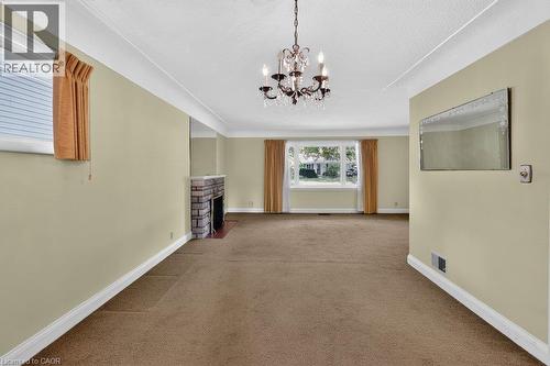 Spacious interior featuring a stone-clad fireplace and a chandelier light fixture - 948 Long Drive, Burlington, ON 