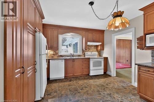Kitchen featuring wood cabinetry, stone-look tile flooring, and a tile backsplash - 948 Long Drive, Burlington, ON 
