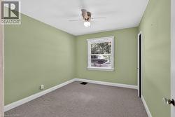 Carpeted room with a ceiling fan, white trim, and a window with blinds - 