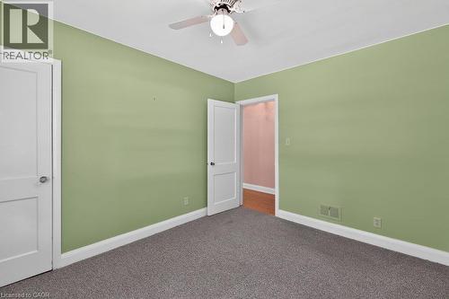 Wall-to-wall carpeting, light green painted walls, white trim, and a ceiling fan with integrated lighting - 948 Long Drive, Burlington, ON 