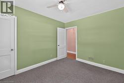Wall-to-wall carpeting, light green painted walls, white trim, and a ceiling fan with integrated lighting - 