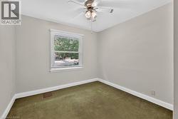 Ceiling fan fixture, window with horizontal blinds, neutral wall paint, and green carpet flooring - 