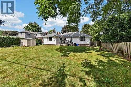 Expansive grassy yard featuring a wood fence, detached storage shed, privacy hedges, and a raised wooden deck - 948 Long Drive, Burlington, ON 
