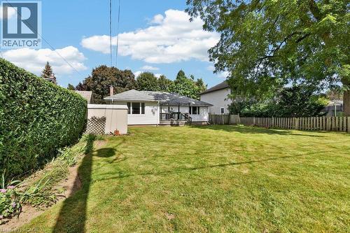 Expansive grassy yard featuring a wood picket fence, mature trees, and a low-maintenance shed - 948 Long Drive, Burlington, ON 