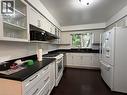 White cabinetry with glass-front uppers, dark countertops, dark wood-finish flooring, a white freestanding range, and a stainless steel sink with a gooseneck faucet - 450 Bridge Street W, Waterloo, ON 