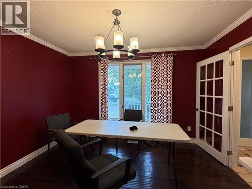 Room featuring a multi-light chandelier, crown molding, dark wood-finish flooring, and French doors with privacy glass - 450 Bridge Street W, Waterloo, ON 