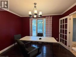 Room featuring a multi-light chandelier, crown molding, dark wood-finish flooring, and French doors with privacy glass - 