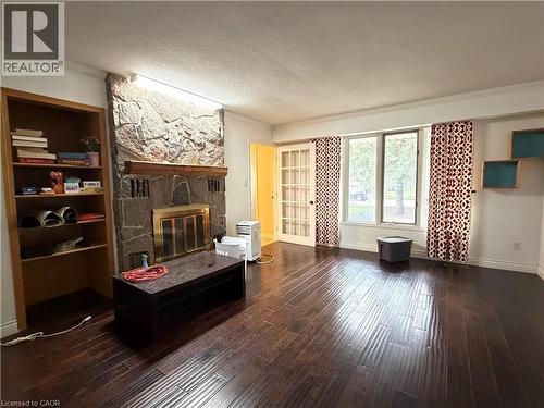Stone-clad fireplace with a wood mantle, built-in shelving, wood-finish flooring, and French doors - 450 Bridge Street W, Waterloo, ON 