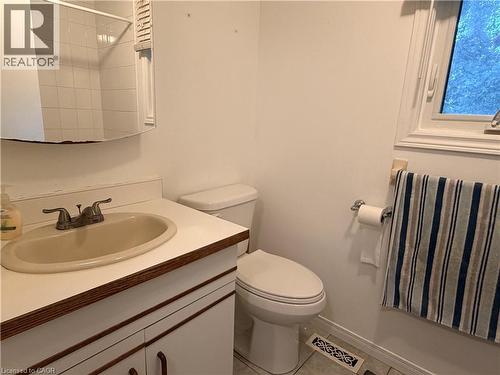 Vanity with integrated sink, wall-mounted mirror, white commode, tiled shower enclosure, and window - 450 Bridge Street W, Waterloo, ON 