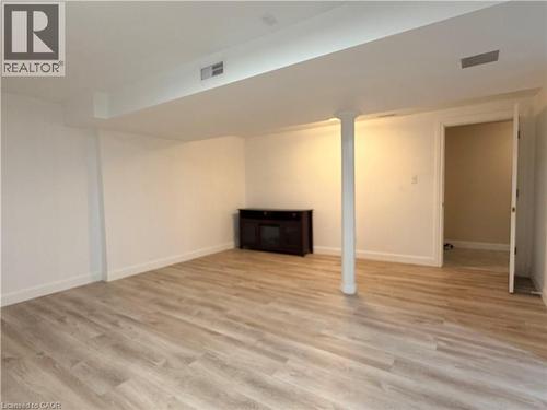Spacious room featuring wood-finish flooring, white walls, and a visible doorway - 450 Bridge Street W, Waterloo, ON 